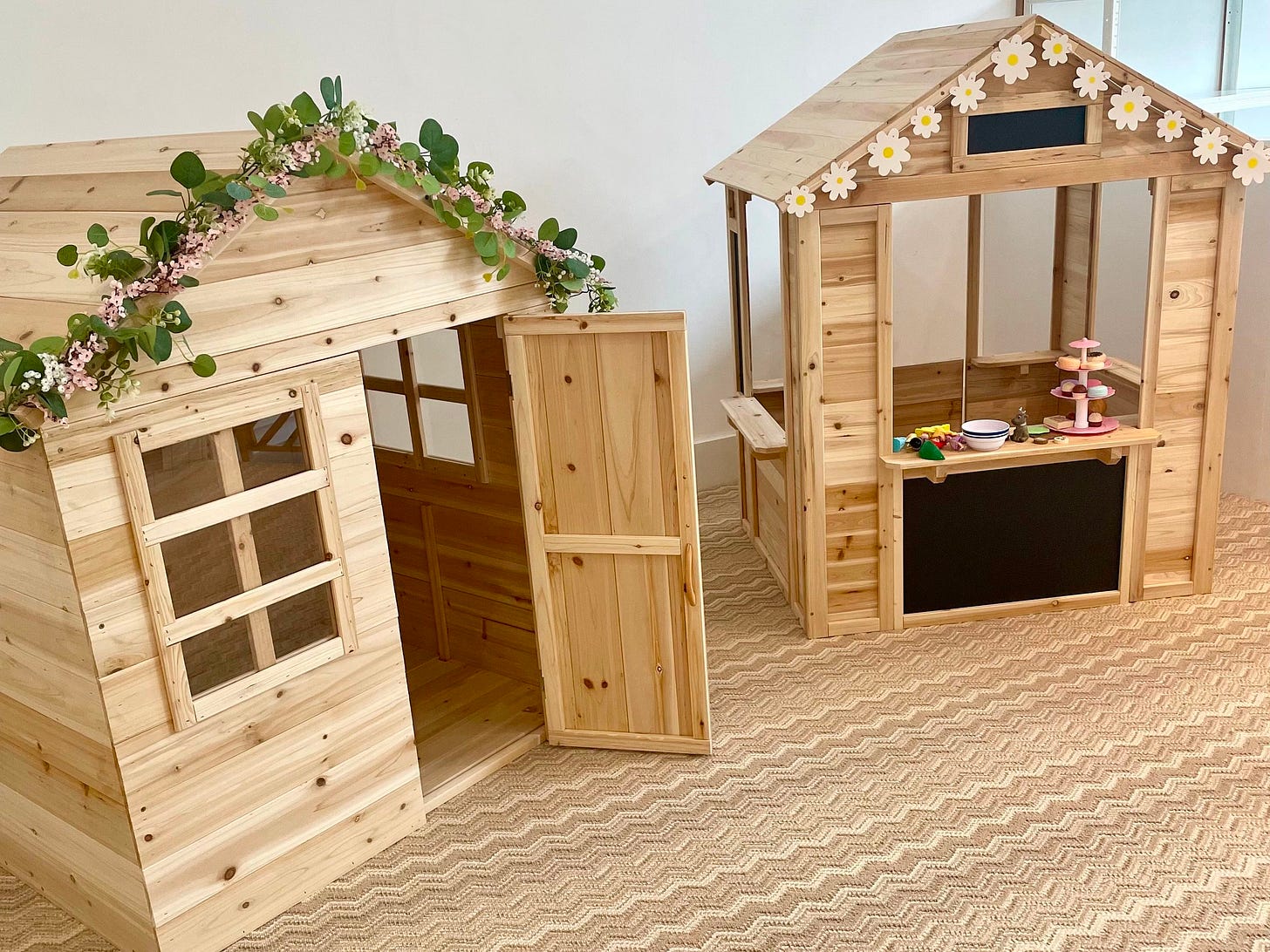 two wooden playhouses with floral decorations