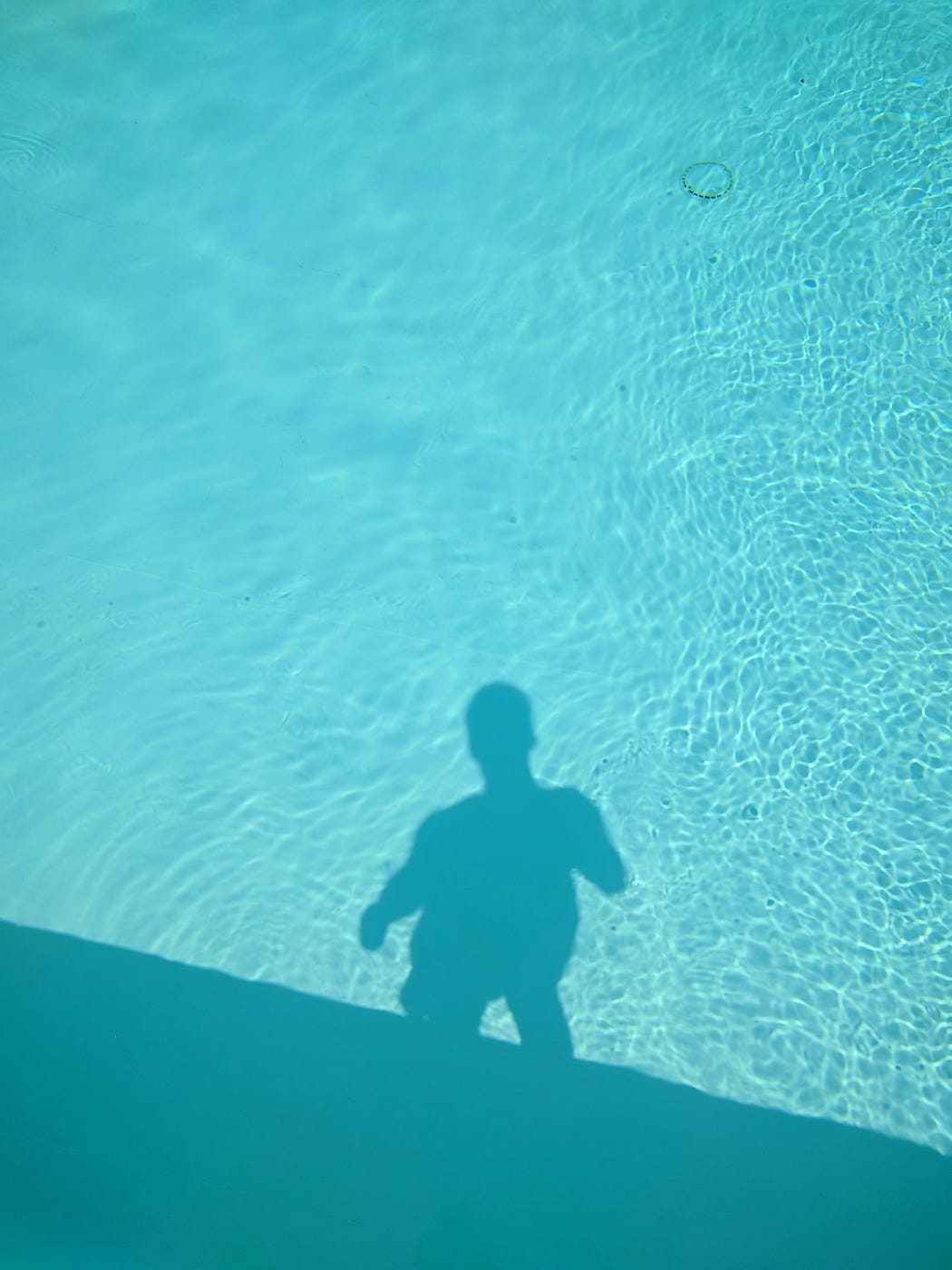 Silhouette of a person in blue reflected on water