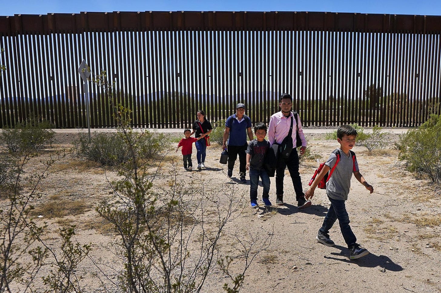 A family of five and a man walk through the desert after crossing the border near Lukeville, Ariz.