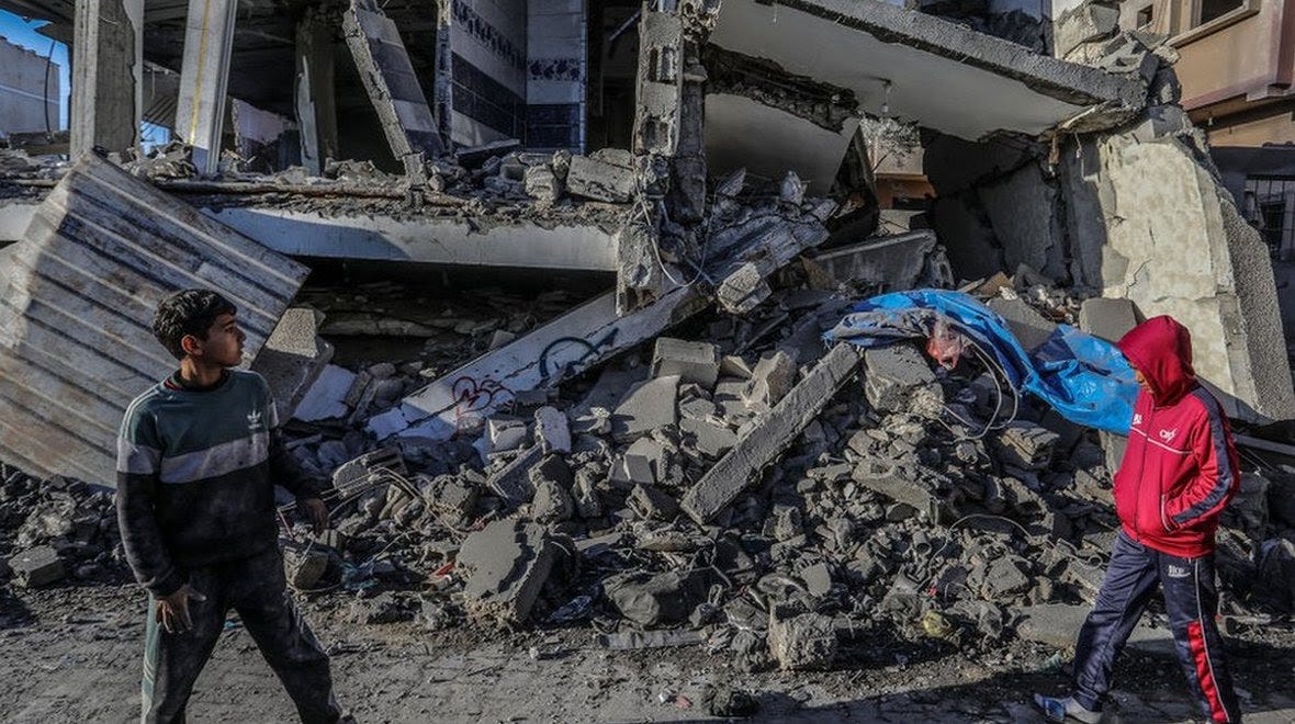 Two children walk amid the rubbles of a collapsed building in Gaza