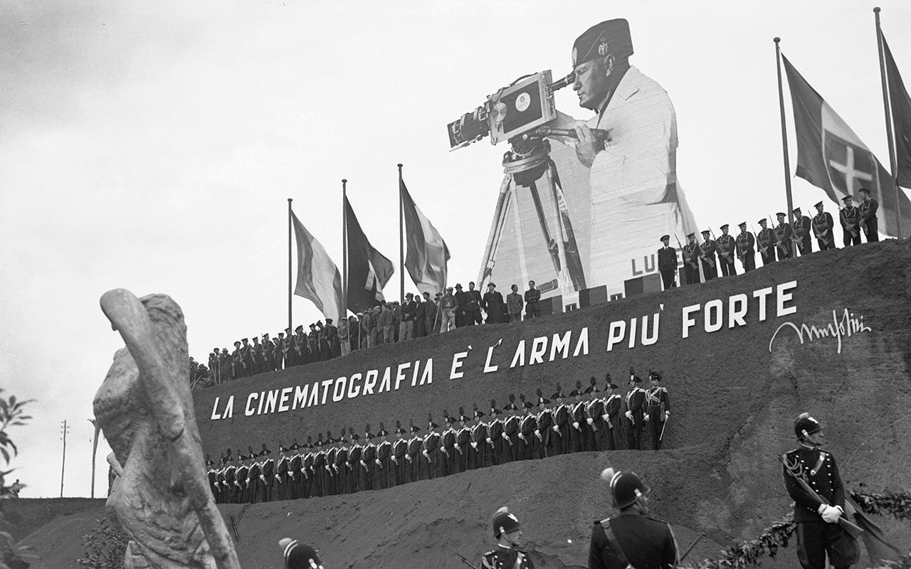 Huge cut-out photograph of Italian fascist dictator Benito Mussolini looking through a cinema camera, above a structure at the Cinecitta film studio in Rome in the 1930s