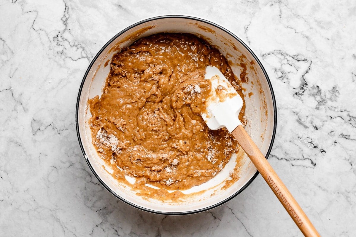 carrot cake muffin batter in mixing bowl with spatula. 
