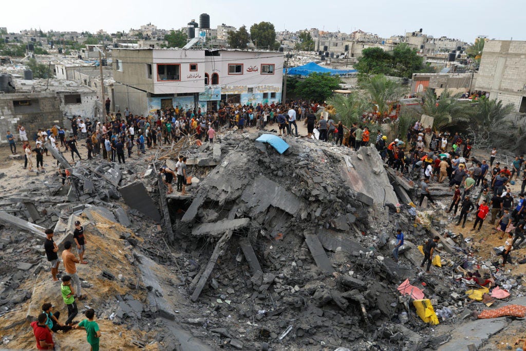 Palestinians gather around the rubble of a building destroyed in Israeli strikes, in the southern Gaza Strip
