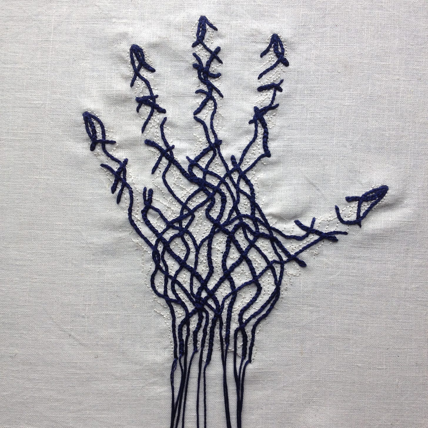 An embroidery on bone white linen. There is the faint outline of a hand, fingers apart. The hand is filled with thick dark blue lines intertwining and crossing over. There are finer thin lines in bone white beneath the thick blue lines. At the wrist, the thick blue lines end in strands of thick thread, hanging over the edge of the linen.