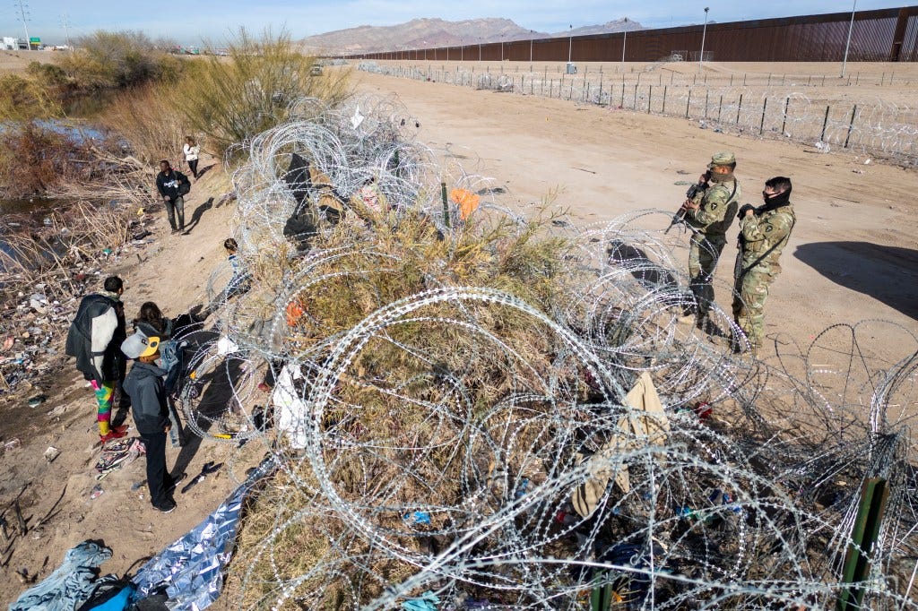 een from an aerial view, Texas National Guard troops watch over immigrants on the other side of razor wire after they crossed into El Paso, Texas on Jan. 30.