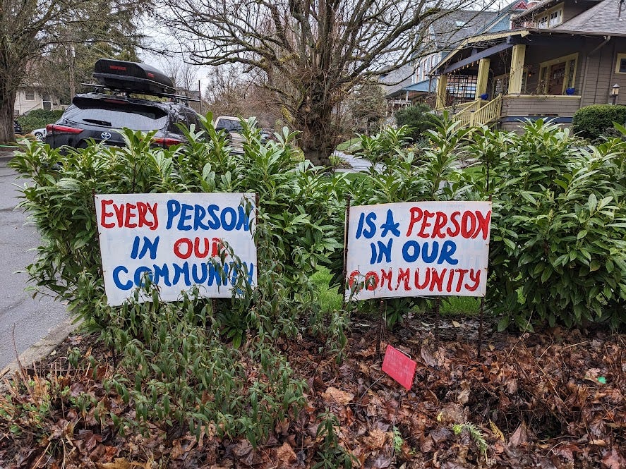 handmade signs that read "every peson in our community is a person in our community"