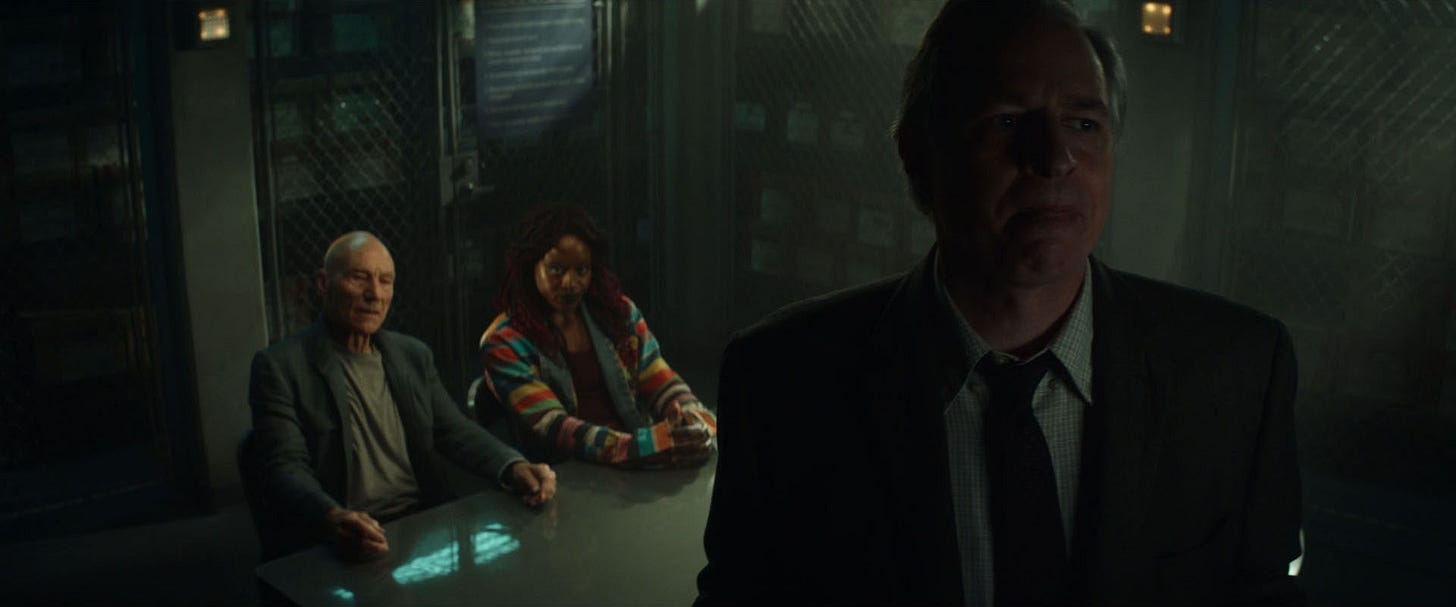 This image from "Mercy" (Star Trek: Picard Season 2's eighth episode) shows FBI Agent Martin Wells (played by Jay Karnes) standing in the foreground with his back to Jean-Luc Picard (played by Patrick Stewart) and Young Guinan (played by Ito Aghayere), who sit side-by-side at the same table seen in the above photo. This image from "Mercy" (Star Trek: Picard Season 2's eighth episode) shows FBI Agent Martin Wells (played by Jay Karnes) standing in the foreground with his back to Jean-Luc Picard (played by Patrick Stewart) and Young Guinan (played by Ito Aghayere), who sit side-by-side at the same table seen in the above photo.