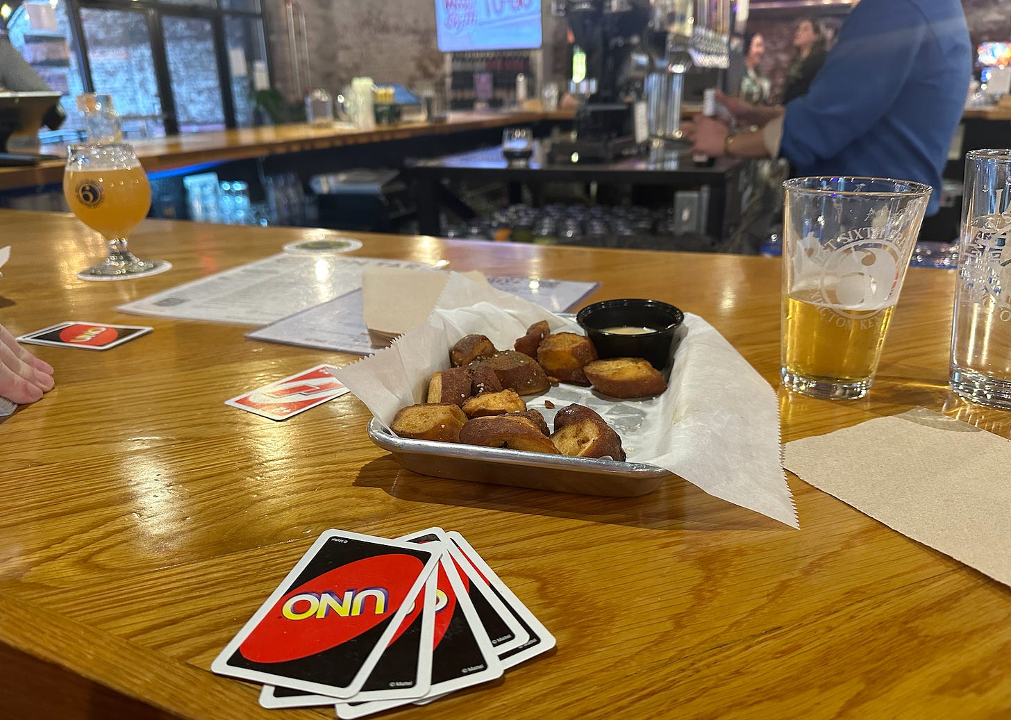 picture of a bar with uno cards, pretzel bites, and pints of alcohol