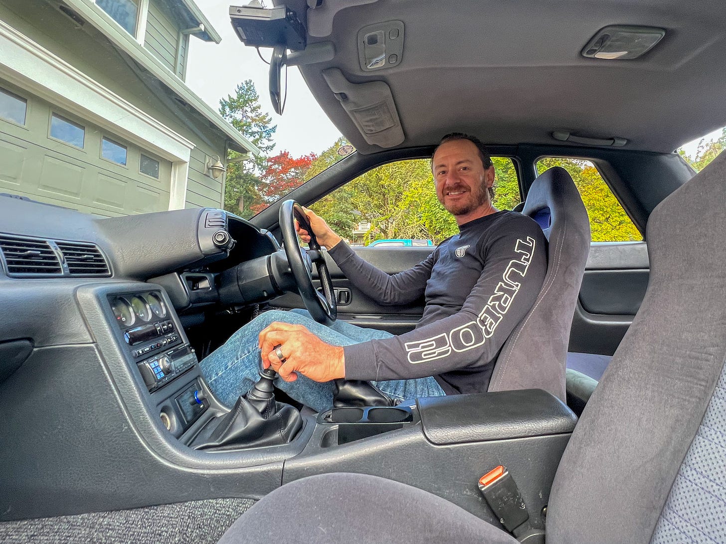 Ryan ZumMallen, author of 'Cult of GT-R,' smiling at the camera from behind the wheel of an R32 Skyline GT-R once owned by MotoRex founder Hiro Nanahoshi.