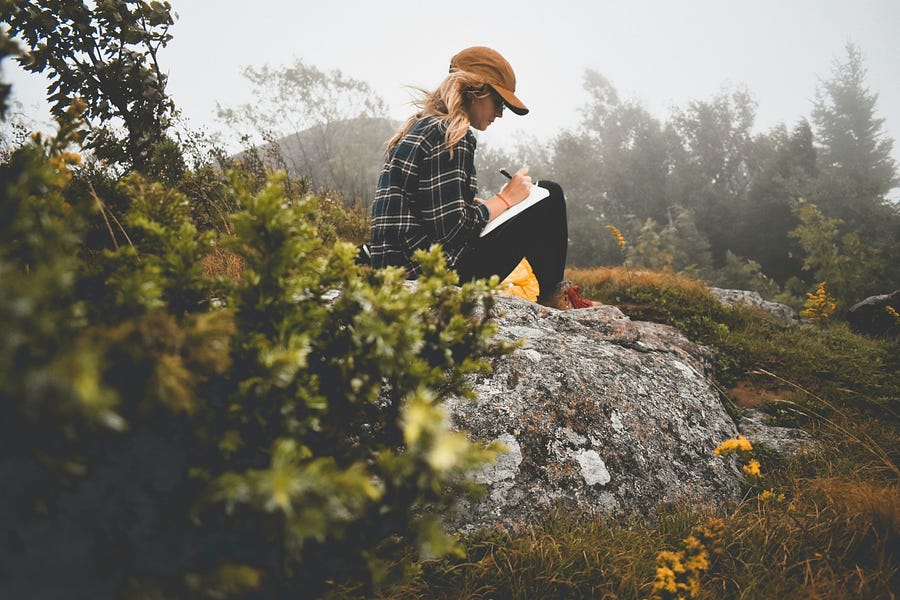 Girl writing in her journal outdoors.