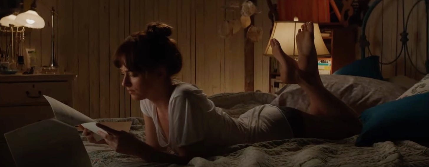 Still from Fifty Shades of Gray: Ana reads a contract lying in bed.