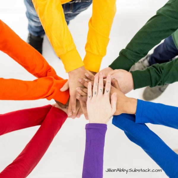 Arms and hands reaching into the center of a circle. Each person is wearing a different color of the rainbow.