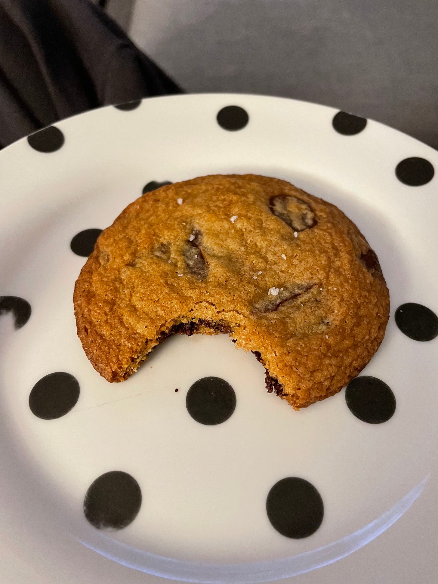 Spotty plate with a browned butter choc chip cookie missing a bite.