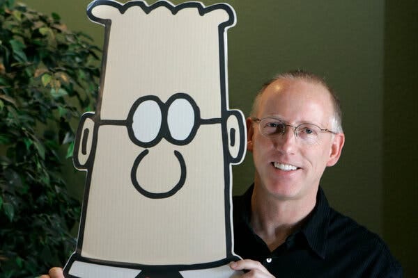 A man in glasses holding a cutout of the main character from the "Dilbert" comic strip.