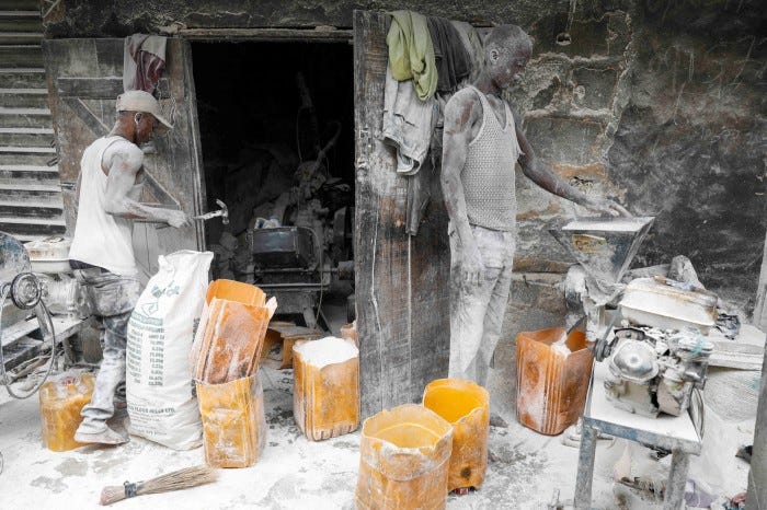 Men grind dried cassava tubers into flour at their shop in Bodija market, Ibadan, Nigeria, in 2022 