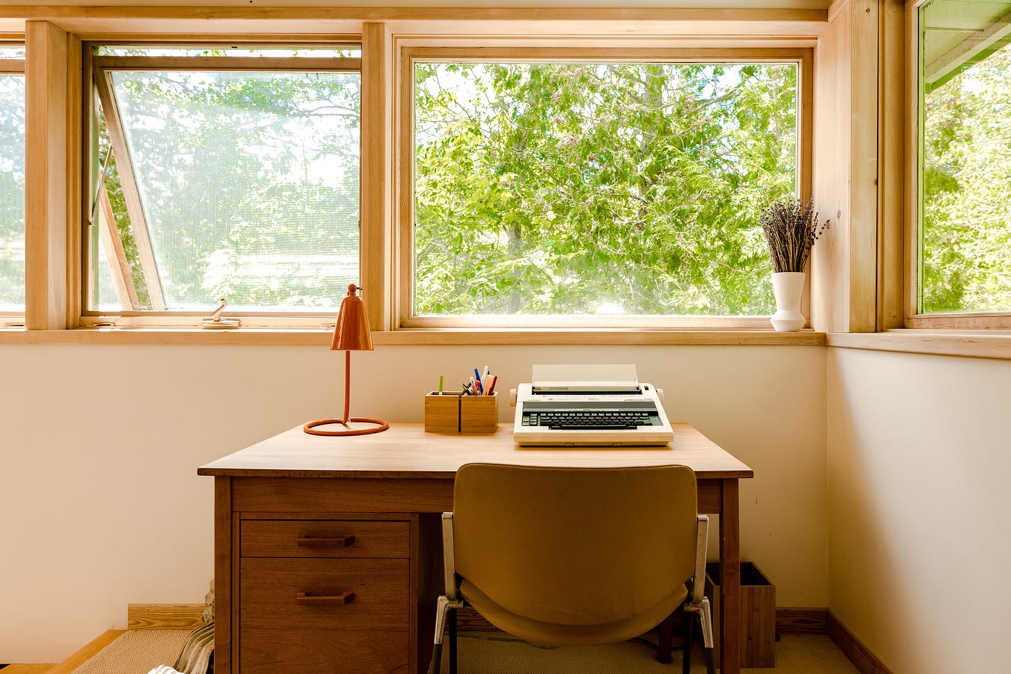 desk by open windows with trees outside