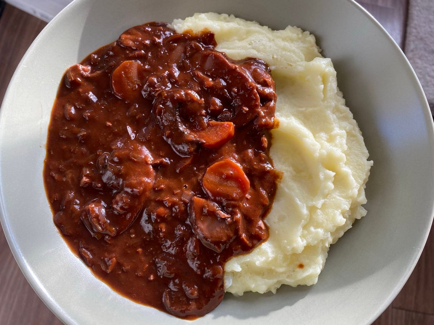 Mushroom bourguignon served on top of mashed potatoes in a green shallow bowl