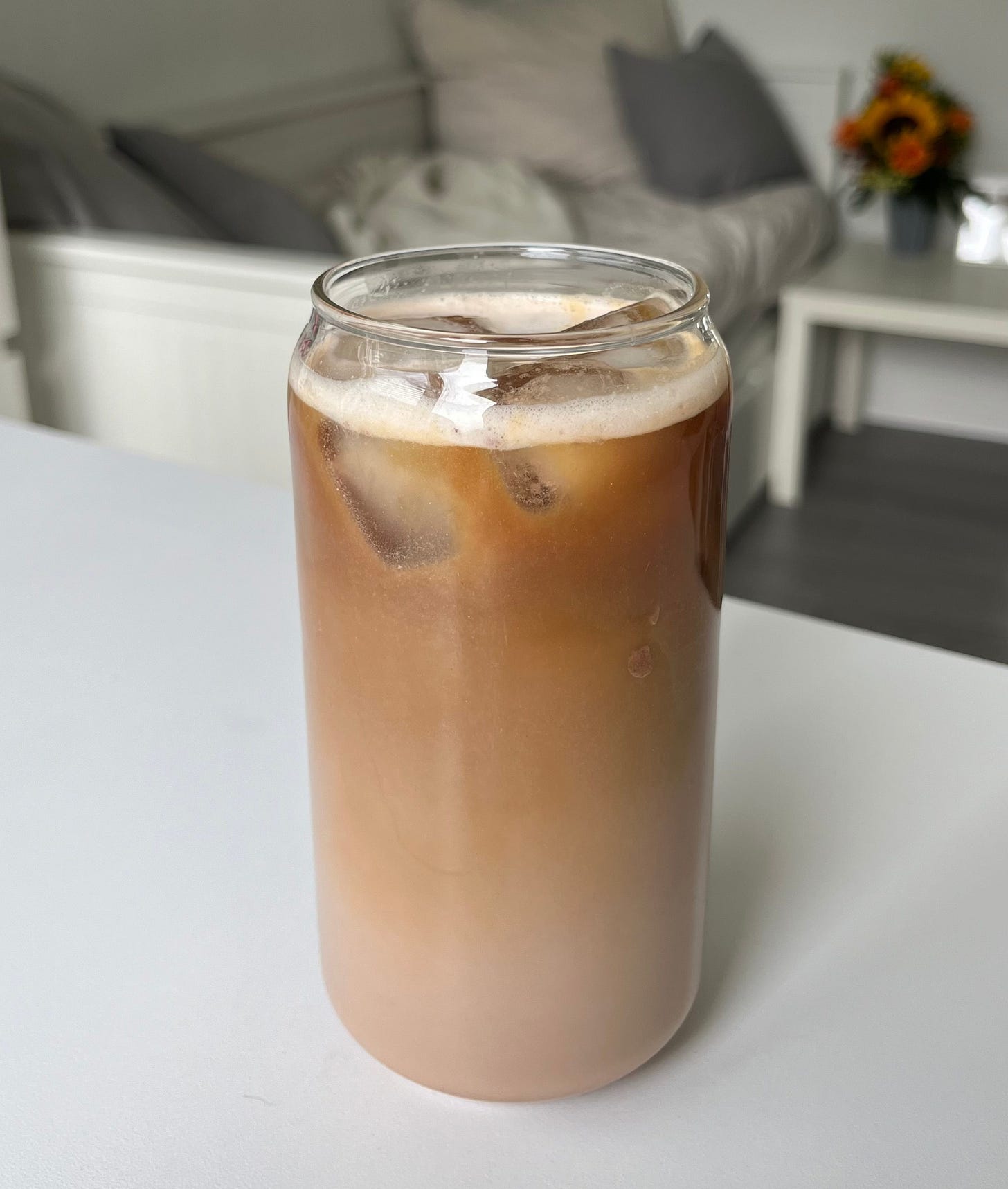 Creamy chocolate protein iced coffee served in a glass with ice cubes and a rich foam topping, perfect for an energizing, protein-packed boost.