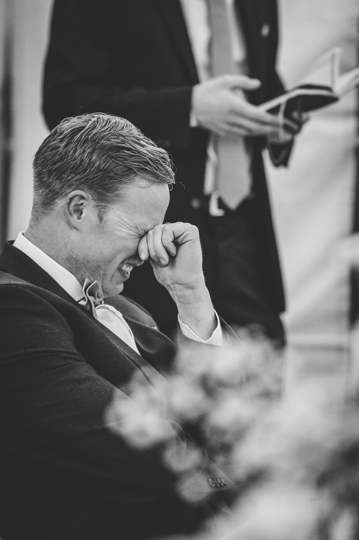 A groom laughing while his bestman gives a speech