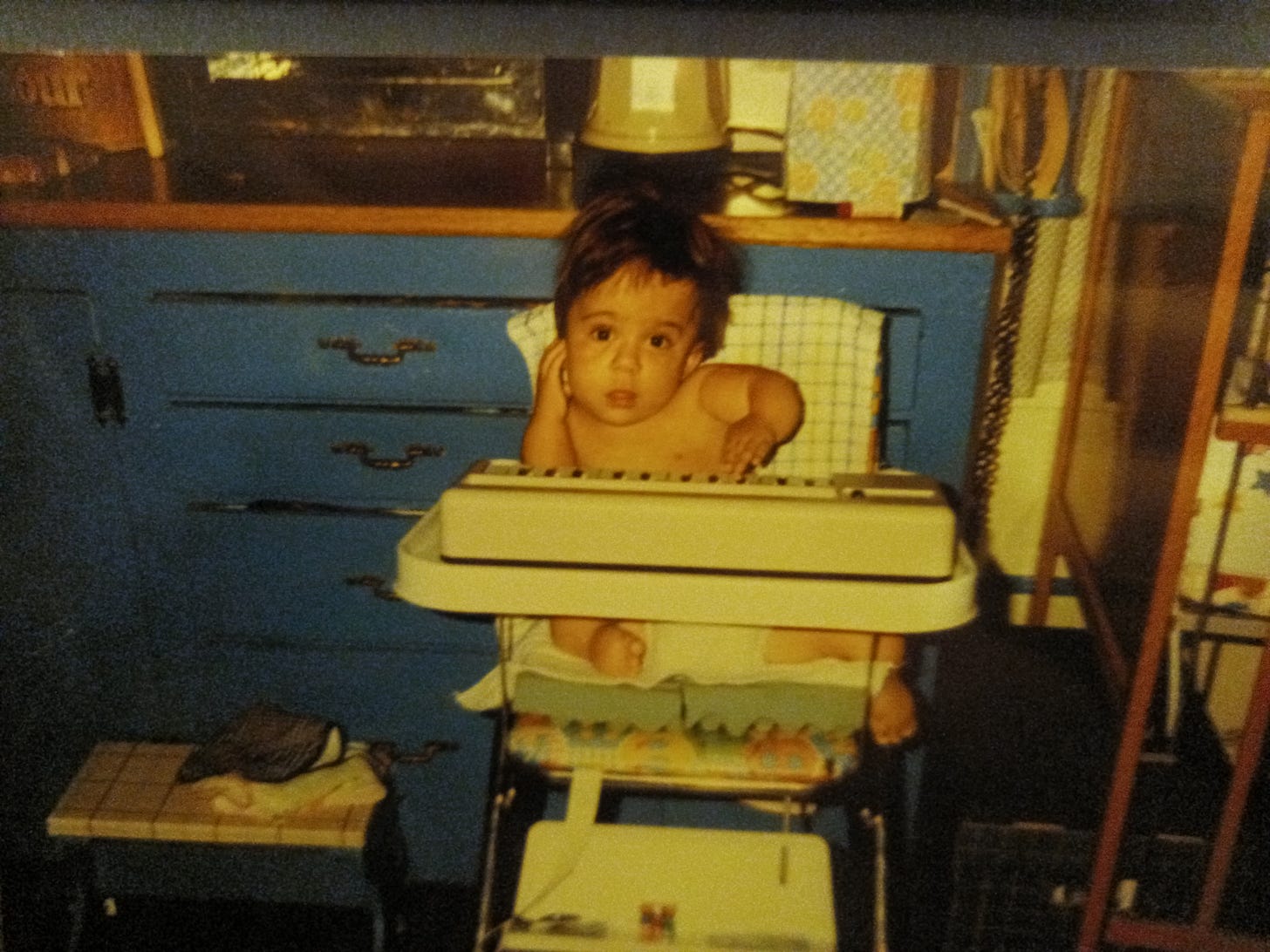 This is a picture of Gaelynn as a baby, wearing only a diaper and sitting in a high chair. Her arms and legs are visibly bent, but nonetheless she is adorable (if I do say so myself).