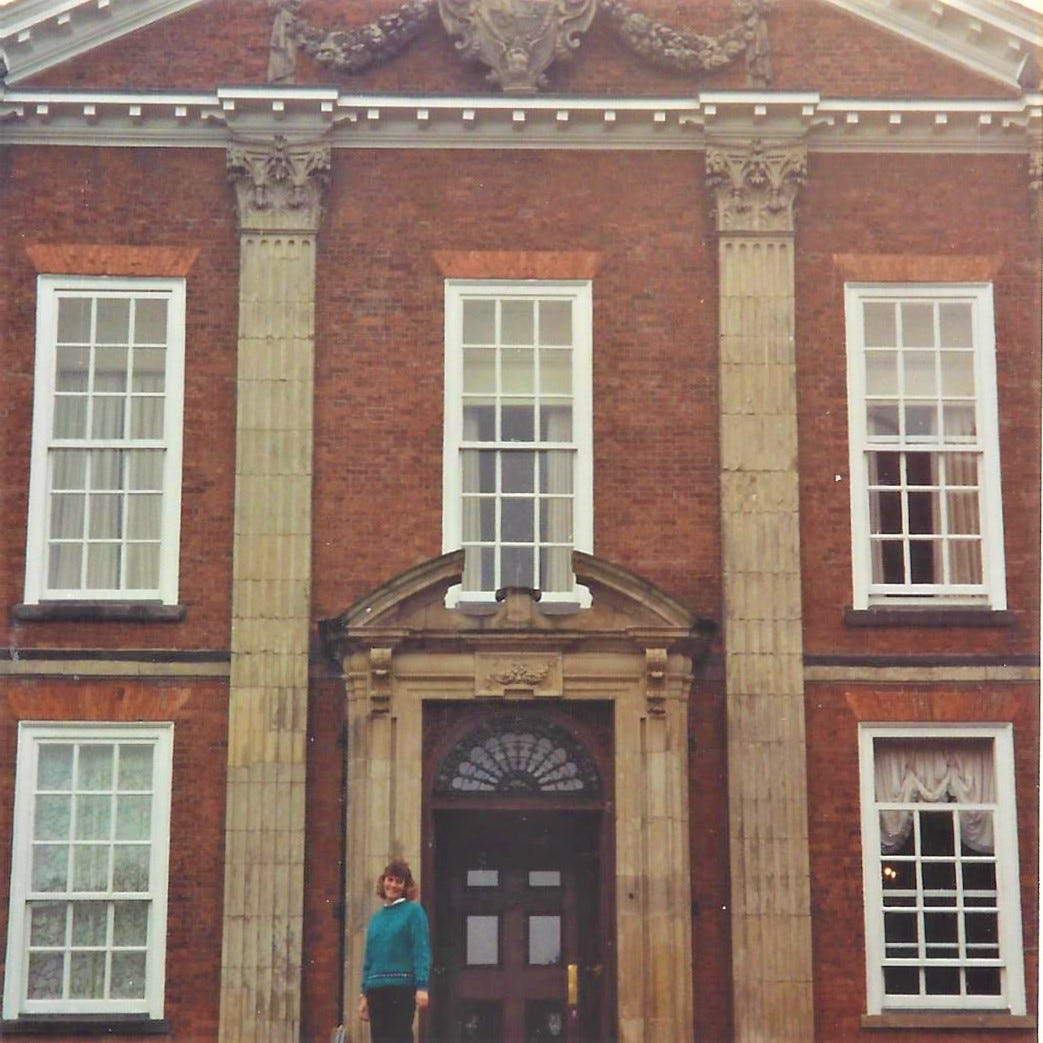 20-something woman stands at the front door of impressive British country  manor house turned hotel, Bosworth Hall
