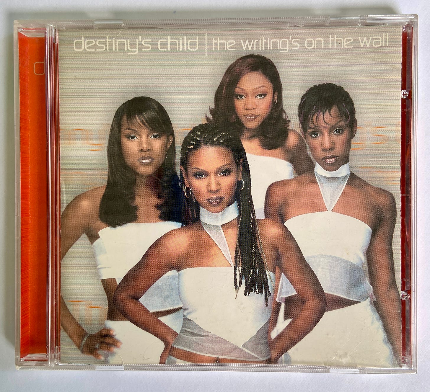 the CD case for Destiny's Child album The Writing's on The Wall. four young Black women pose and stare fiercely at the camera while wearing sleek white outfits.