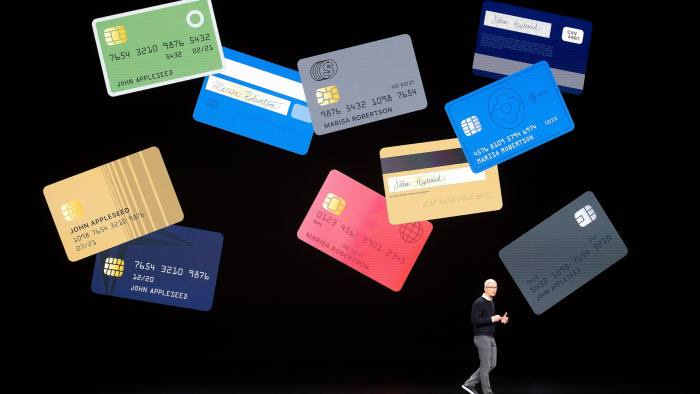 Apple CEO Tim cook on stage with images of credit cards behind him