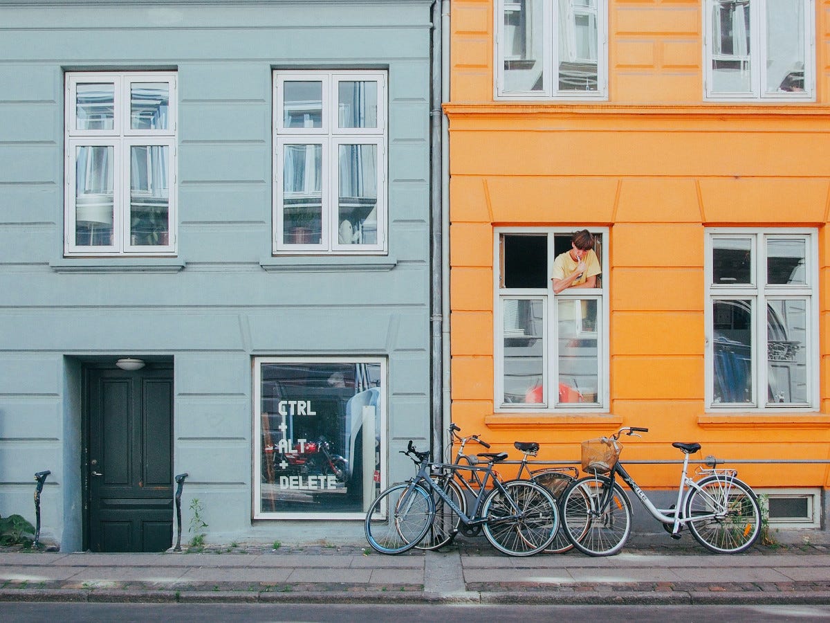 una calle típica de copenhague, con dos casas de colores y varias bicicletas en la acera