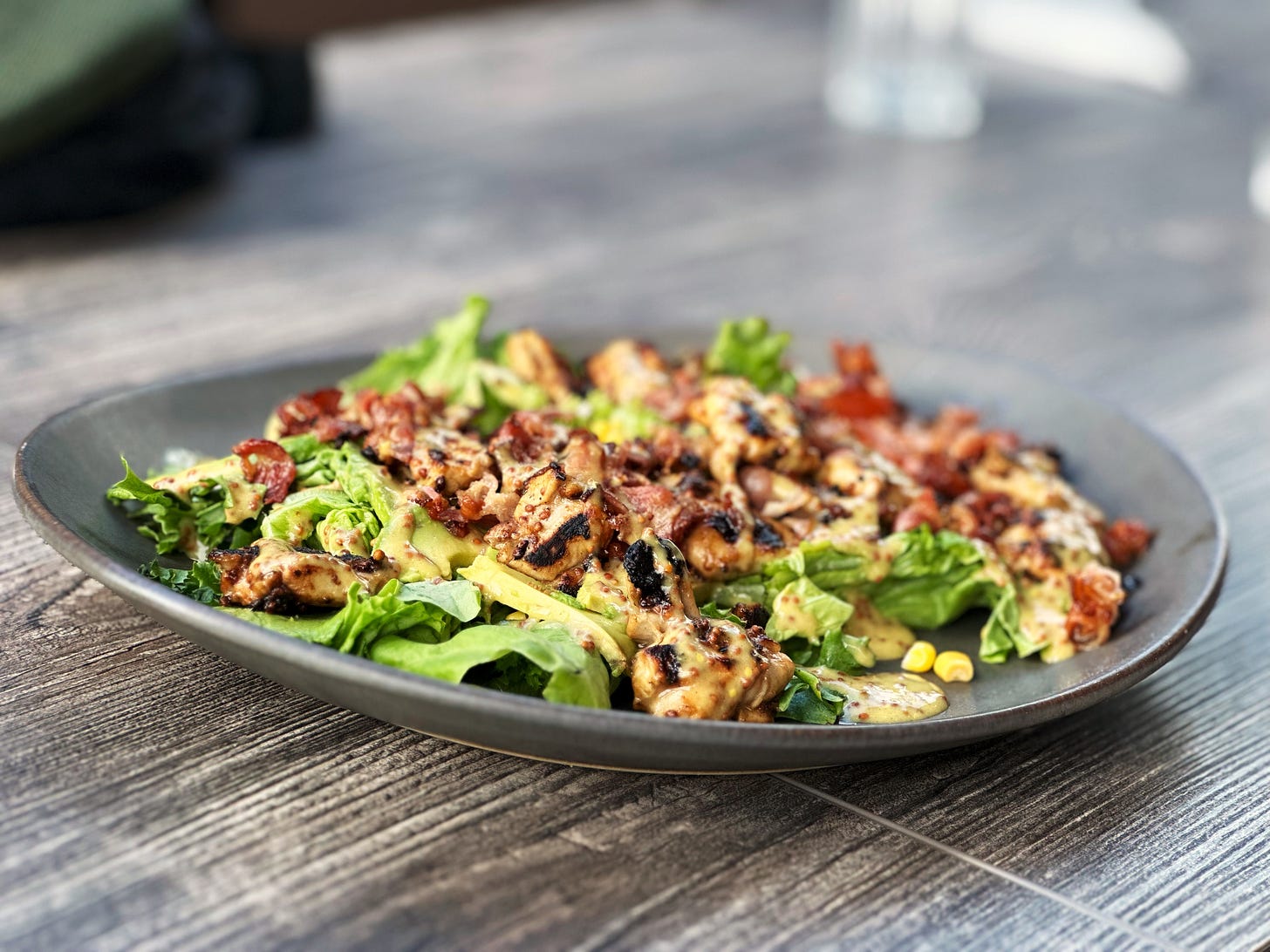 Green salad with mustard chicken, avocado, corn and bacon.