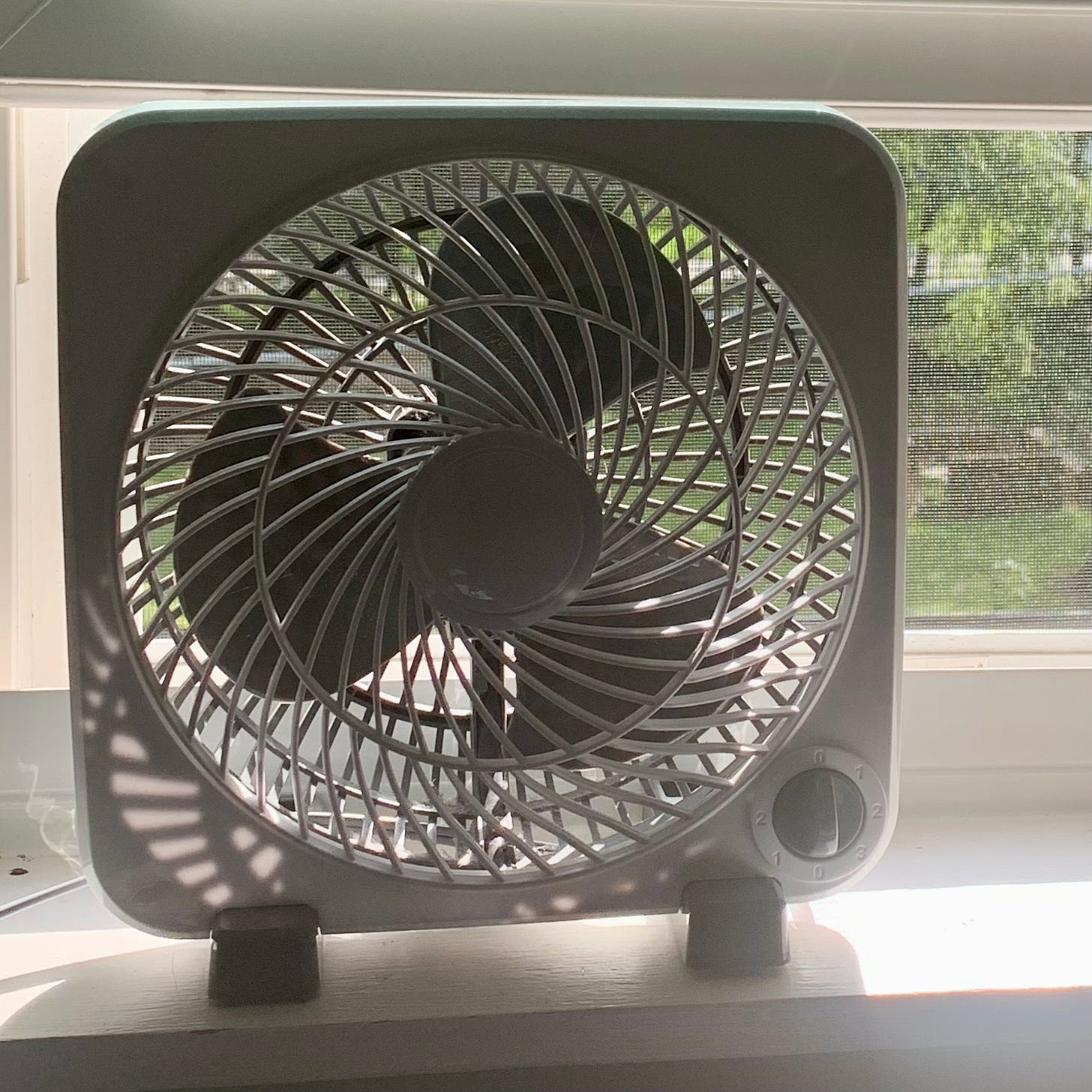 A small box fan on a window sill.