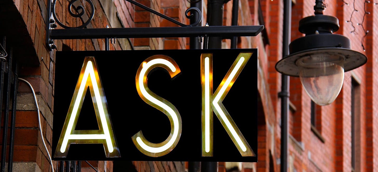 An illuminated street sign sating "ask."