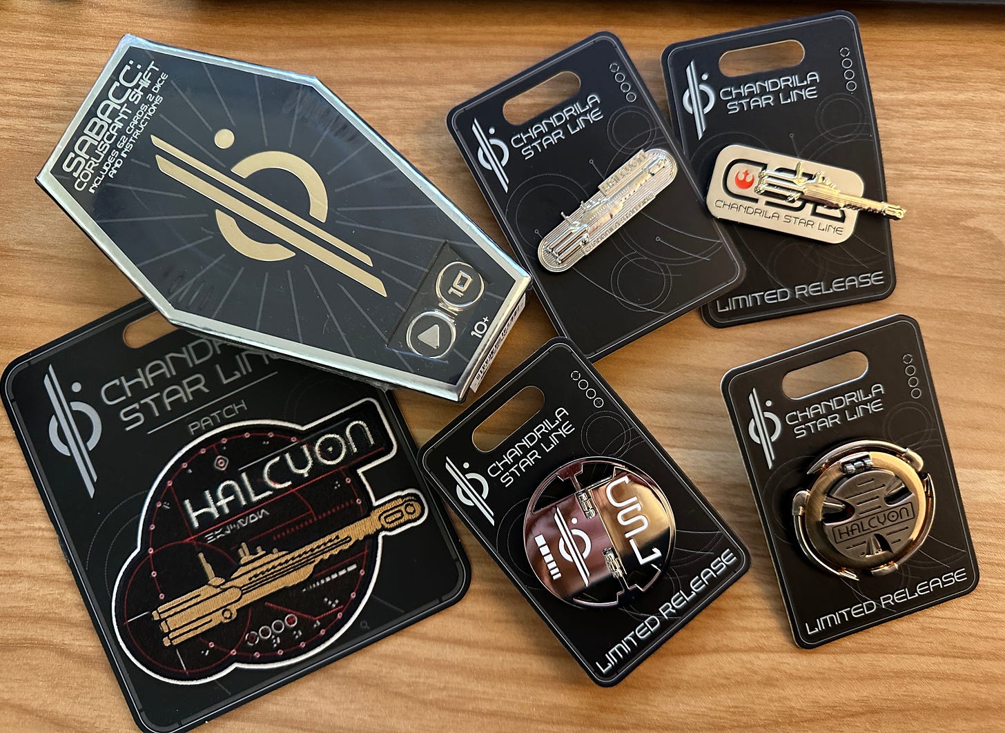 A scattering of Chandrila Star Line branded pins, a patch, and a sabacc set