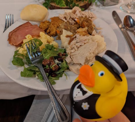 A plate of Thanksgiving dinner with a plastic duck looking at it.