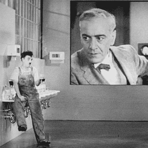 Charlie Chaplin in Modern Times jumps when his boss shouts at him from a huge screen in the bathroom at the factory
