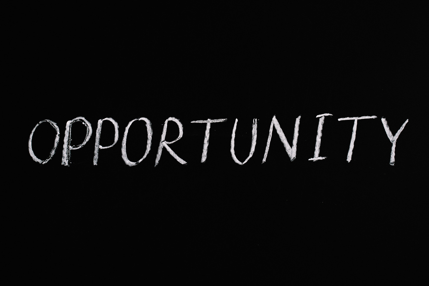 The word opportunity is written in white chalk on a black background