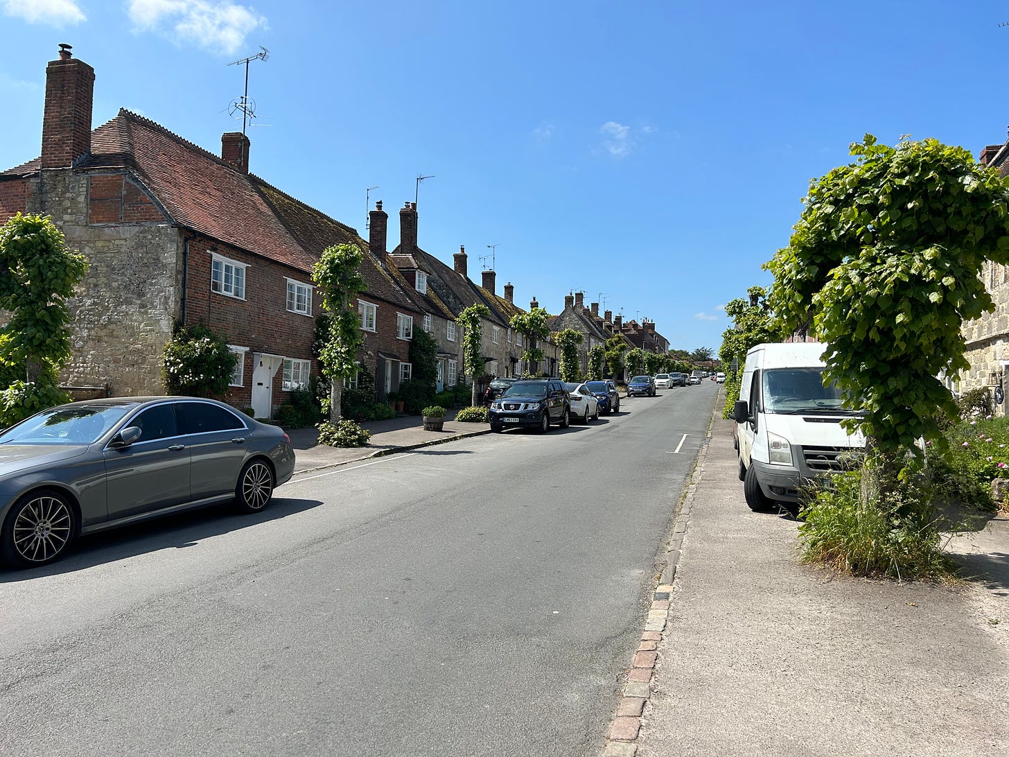 Hindon, Wiltshire. This is the High Street, which is tree lined. The street is on a hillside and has a charming feel to it. On each side are old cottages. Image: Roland's Travels