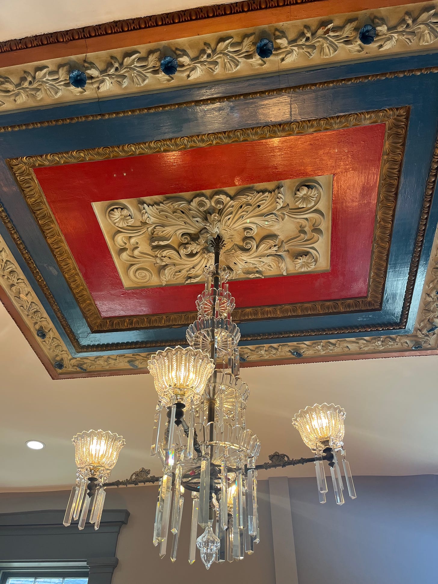 Elaborate plaster ceiling fixture with a crystal chandelier hanging below