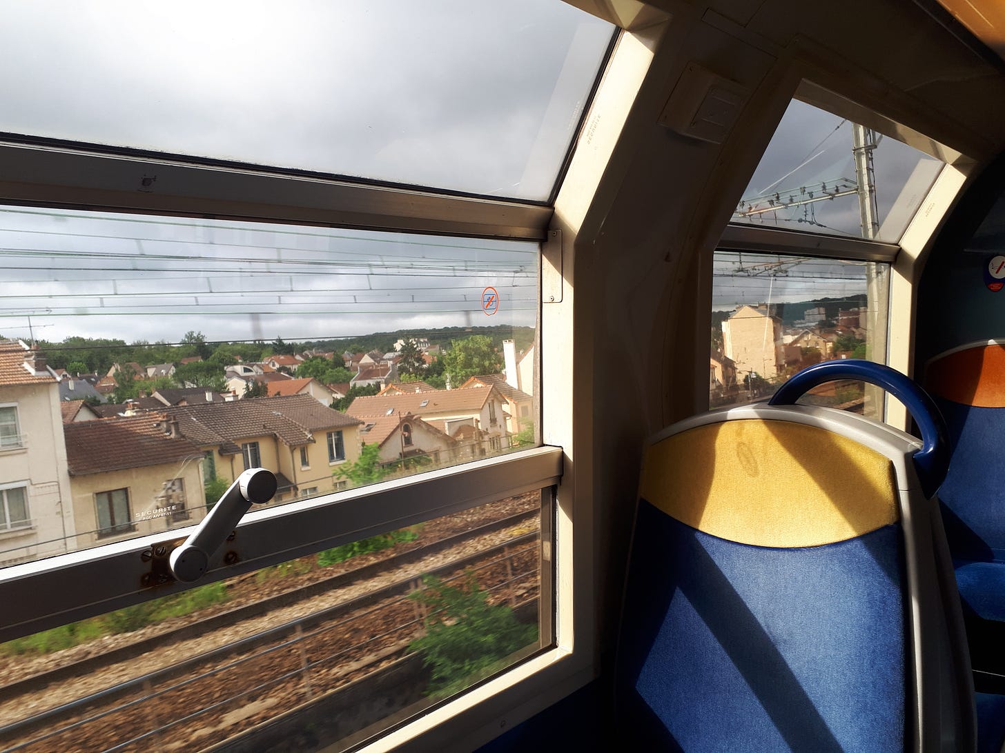 View from inside of a train car, overlooking Paris suburbs.