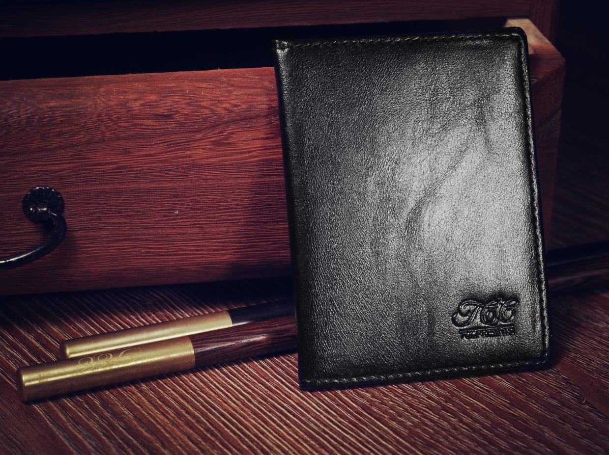 A small leather wallet resting on a wooden draw next to two magic wands.