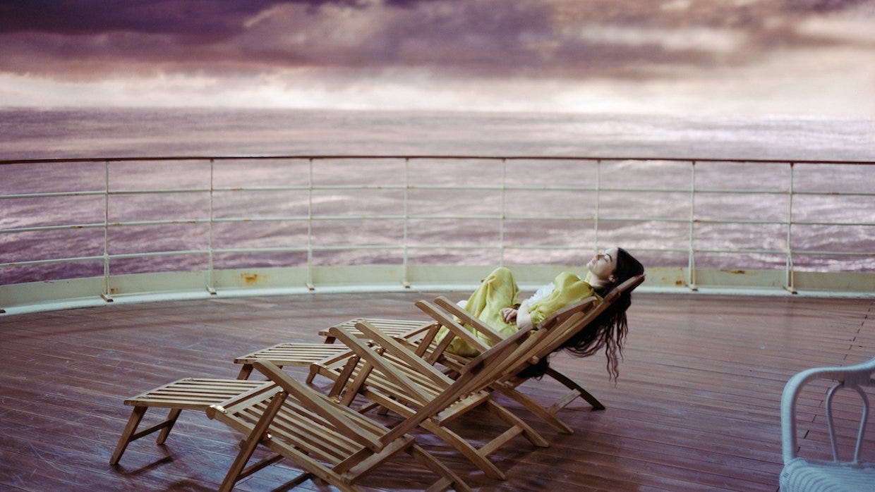 Movie still from Poor Things. A woman lies on a beach chair on a cruise ship.