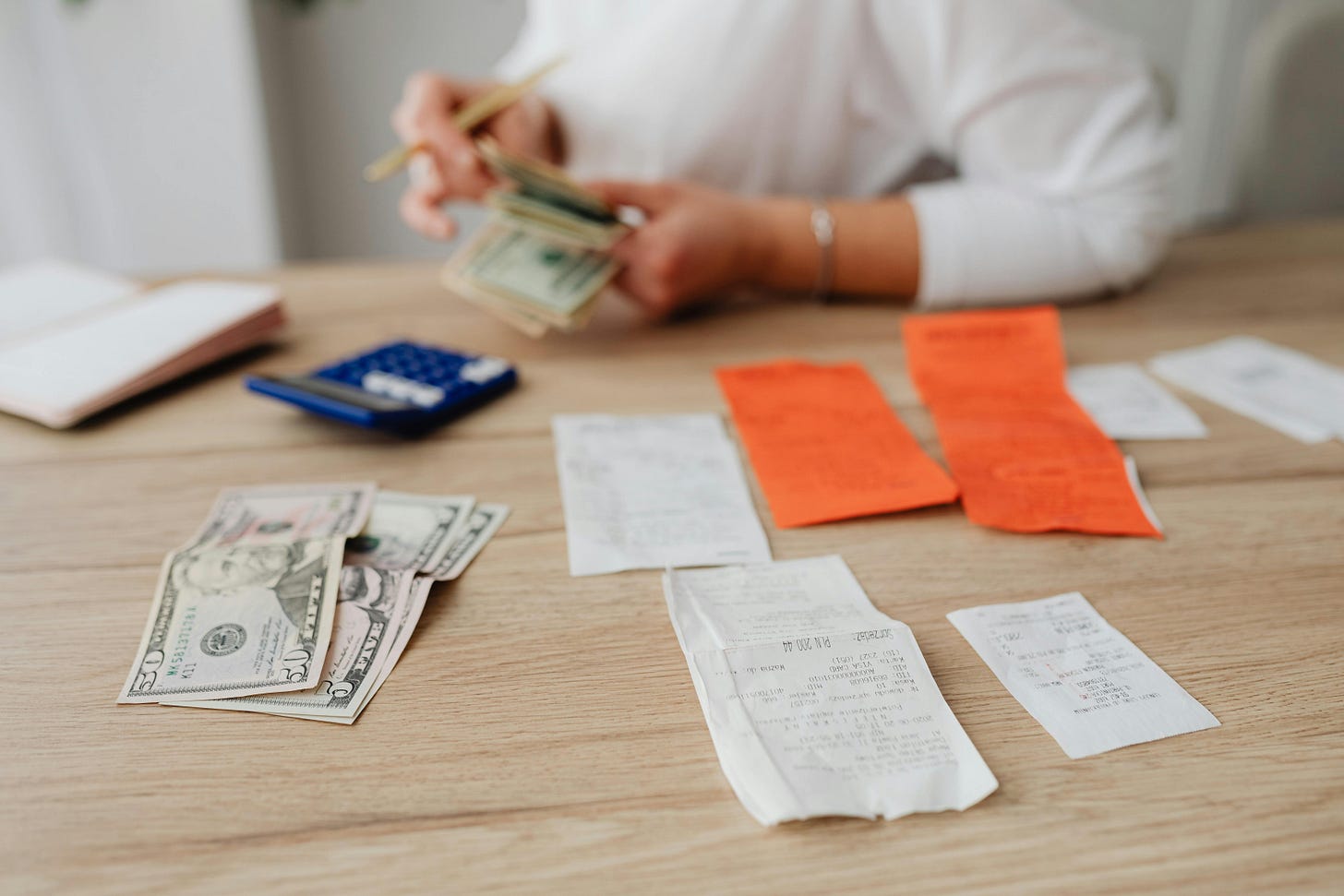 Woman handling receipts and cash on a desk with a calculator. Woman handling receipts and cash on a desk with a calculator.