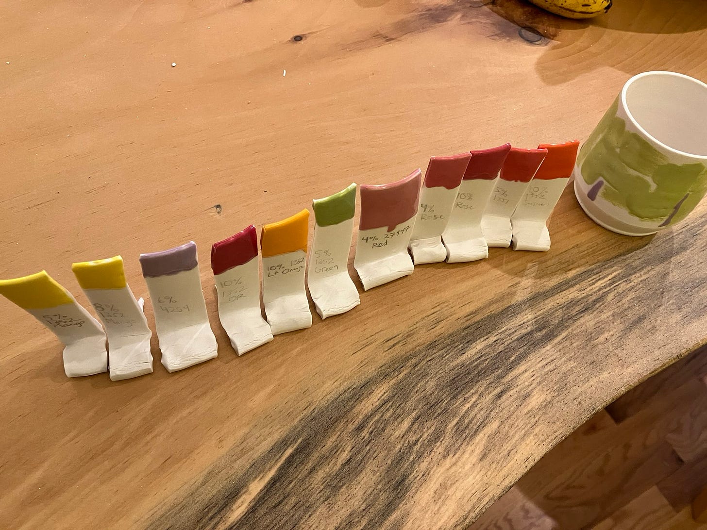 a rainbow of test tiles on a wood table, including reds, orange, yellow, green, and lavender