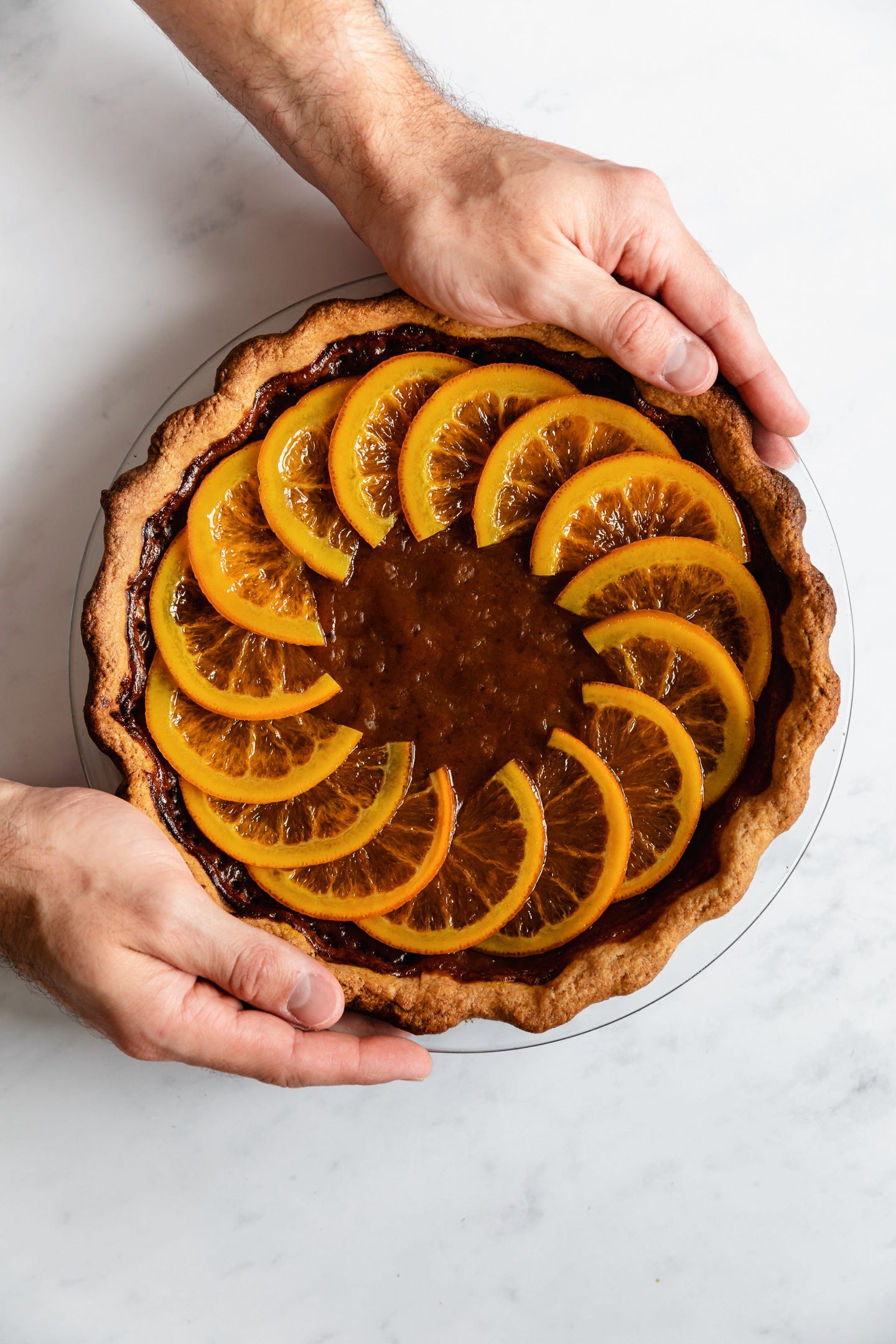 Hands holding vegan candied orange pumpkin pie