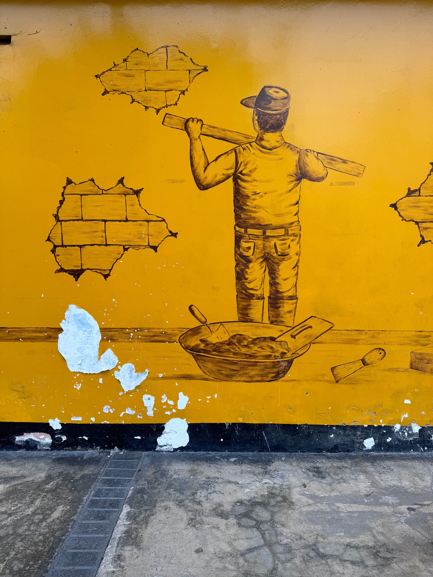 Street art of a construction worker painting over bricks on a yellow wall in Lima, Peru