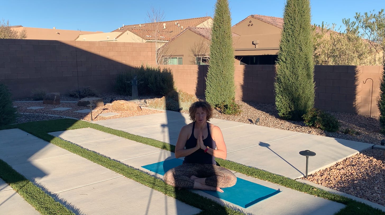 Curly haired woman doing yoga outside with lots of shadows