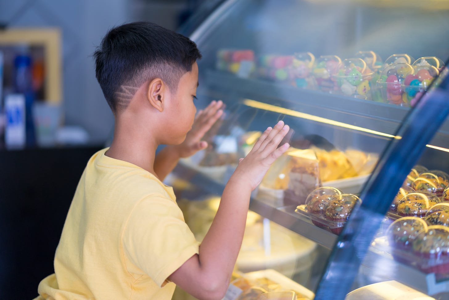 Young Asian boy deciding on a treat at the bakery counter