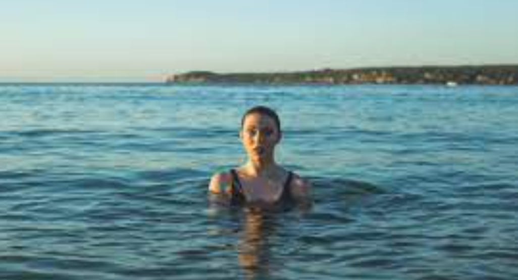Photograph of a young person in the water. They look slightly alarmed.