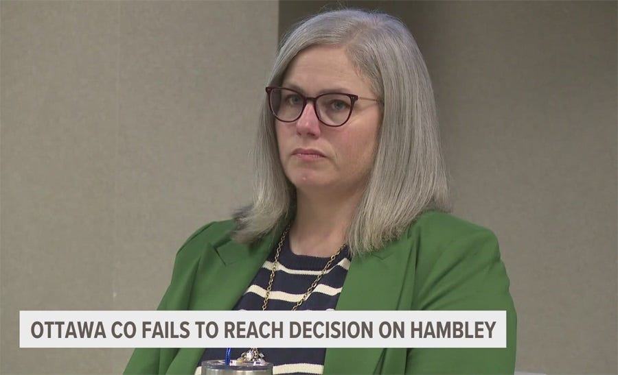 Adeline Hambley, a white woman with grey hair, is pictured during a hearing. Her expression is neutral but also looks vaguely disgusted by her treatment. Maybe we're projecting.