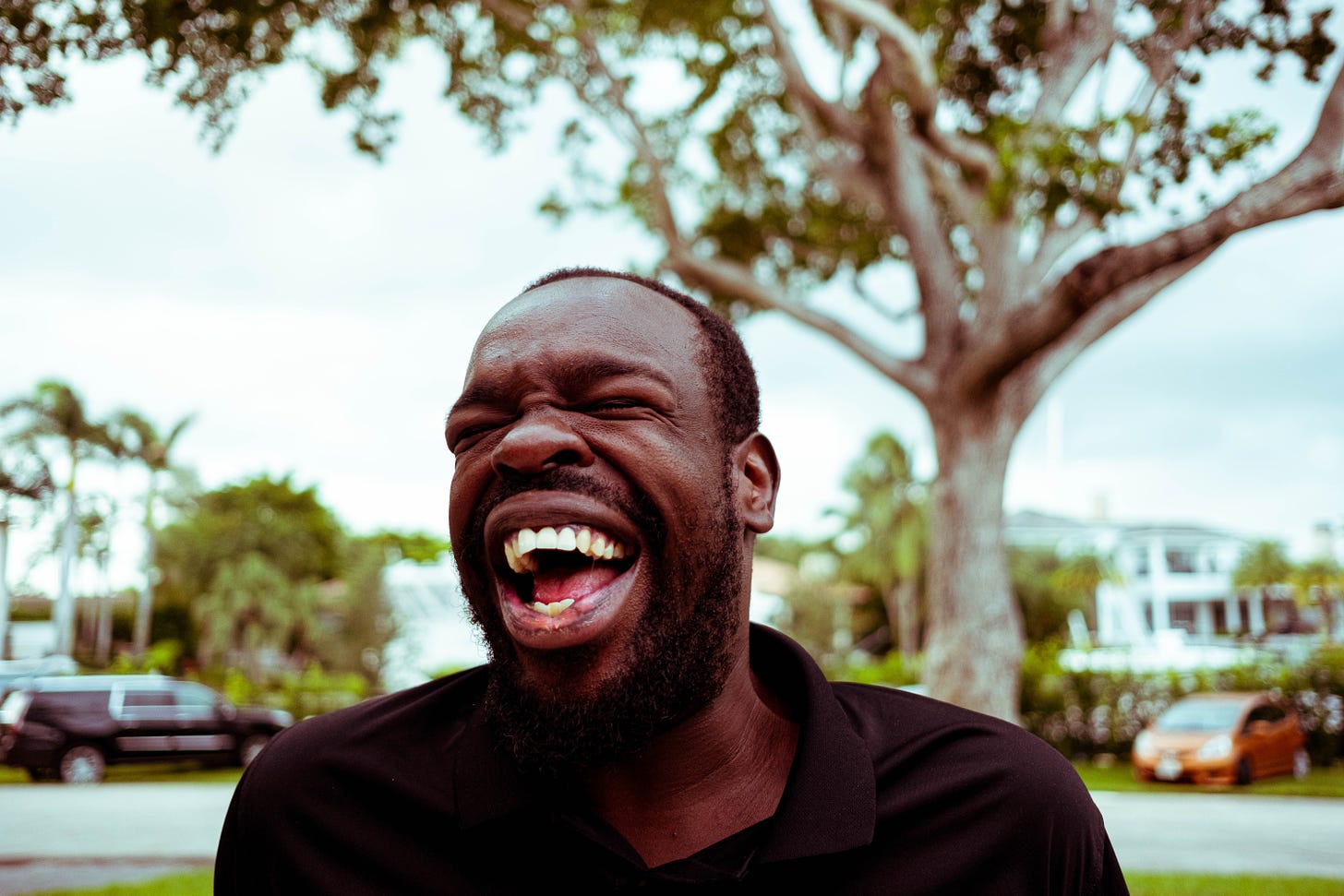 Happy black man laughing outside in a yard