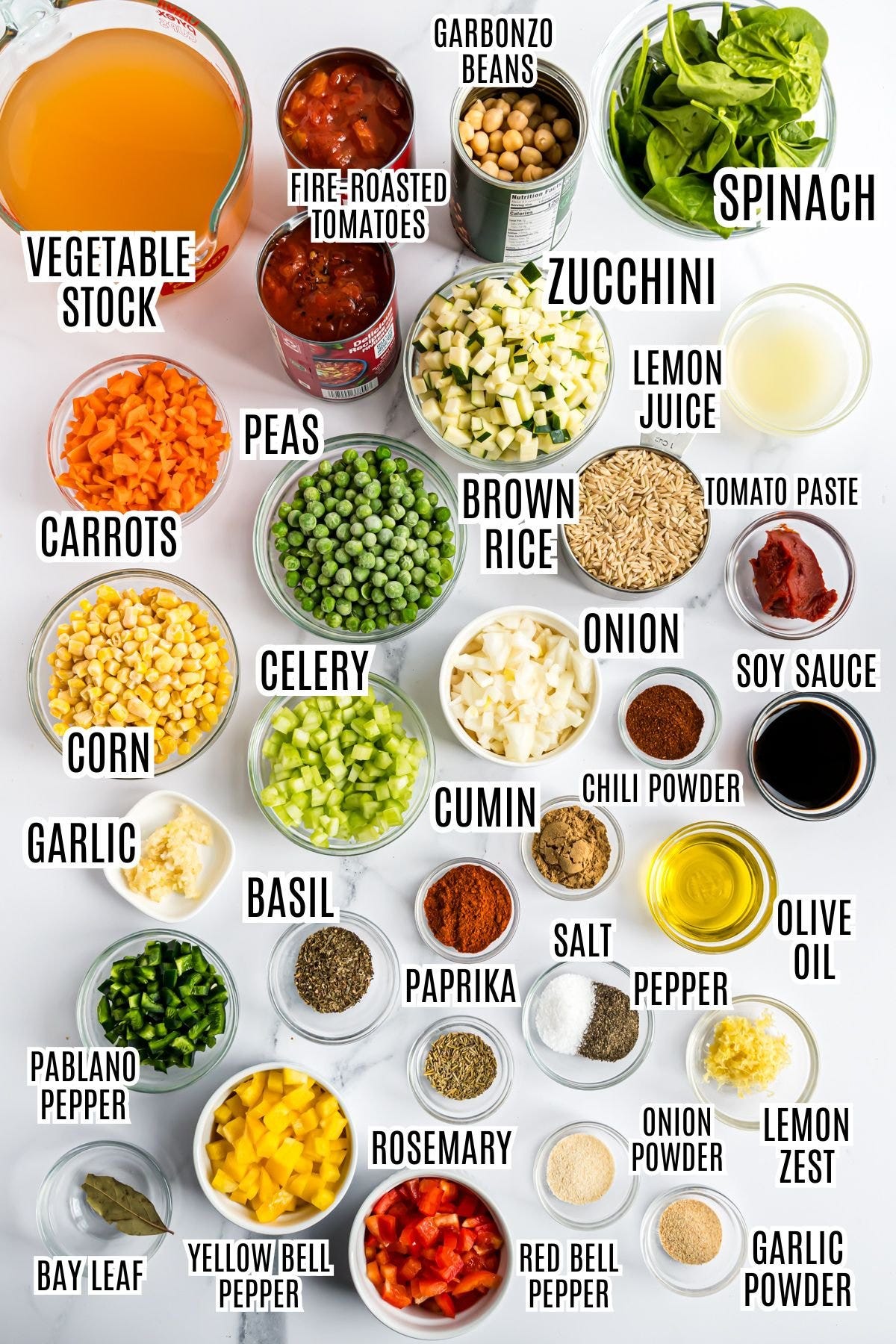 The ingredients needed to make this vegetable soup include: vegetable stock, fire-roasted tomatoes, garbanzo beans, spinach, carrots, frozen peans, zucchini, lemon juice, frozen corn, celery, brown rice, tomato paste, onion, soy sauce, chili powder, cumin, garlic, poblano pepper, basil, paprika, salt, pepper, olive oil, bay leaf, yellow and red bell pepper, onion powder, garlic powder, and lemon zest.